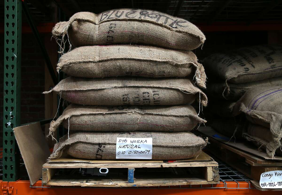Burlap sacks of coffee beans, each weighing 60 kilograms, are stacked in the warehouse at the Blue Bottle Coffee roasting plant in Oakland, Calif. on Wednesday, Jan. 14, 2015