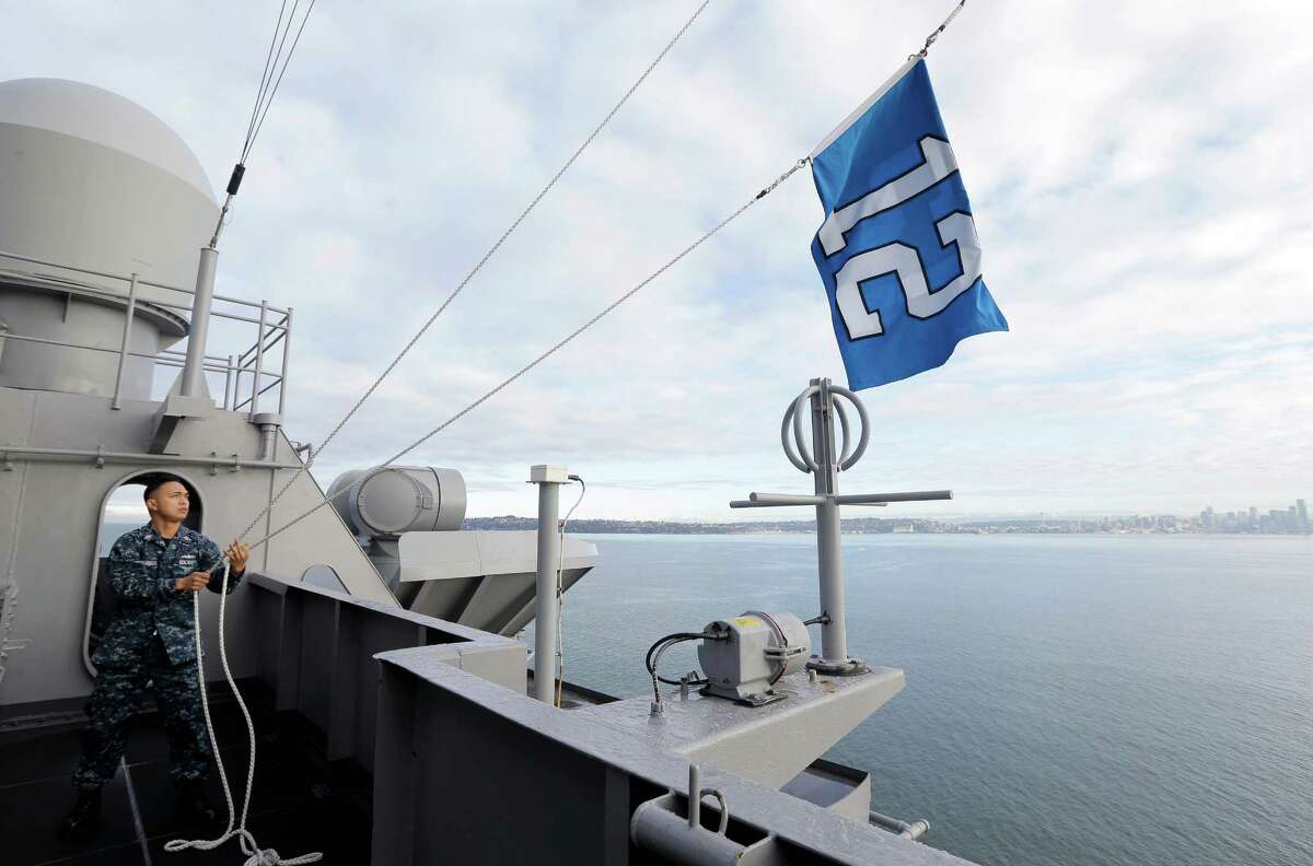 U.S. Navy Quartermaster 1st Class Dave Macaraeg demonstrates how the Seattle Seahawks' 12th Man flag is hoisted up and down while it is flying on the the USS John C. Stennis Navy Aircraft Carrier as the ship moves past Seattle from Naval Base Kitsap in Bremerton to Naval Magazine Indian Island to take on ammunition before a deployment the the Pacific Ocean near San Diego. The Seahawks will play the Green Bay Packers on Sunday, Jan. 18, 2015 in the NFC championship NFL football game.