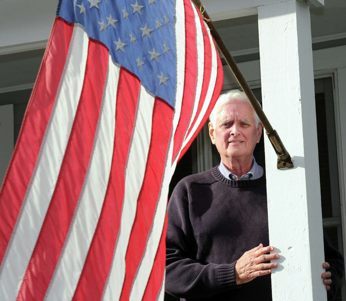 The newly sworn in Greenwich Selectman John Toner stands by the American Flag at his home in the Glenville section of Greenwich, Conn., Friday, Jan. 16, 2015.