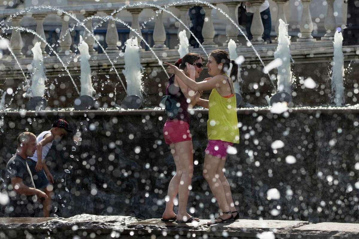 FILE - In this July 30, 2014 file photo, girls cool themselves in a fountain after a sunny and hot day in Alexandrov Garden at the Kremlin Wall in Moscow, Russia. Federal science officials announced Friday that for the third time in a decade, the globe sizzled to the hottest year on record. Both the National Oceanic and Atmospheric Administration and NASA calculated that in 2014 the world had its hottest year in 135 years of record-keeping. Earlier, the Japanese weather agency and an independent group out of University of California Berkeley also measured 2014 as the hottest on record. (AP Photo/Alexander Zemlianichenko, File)