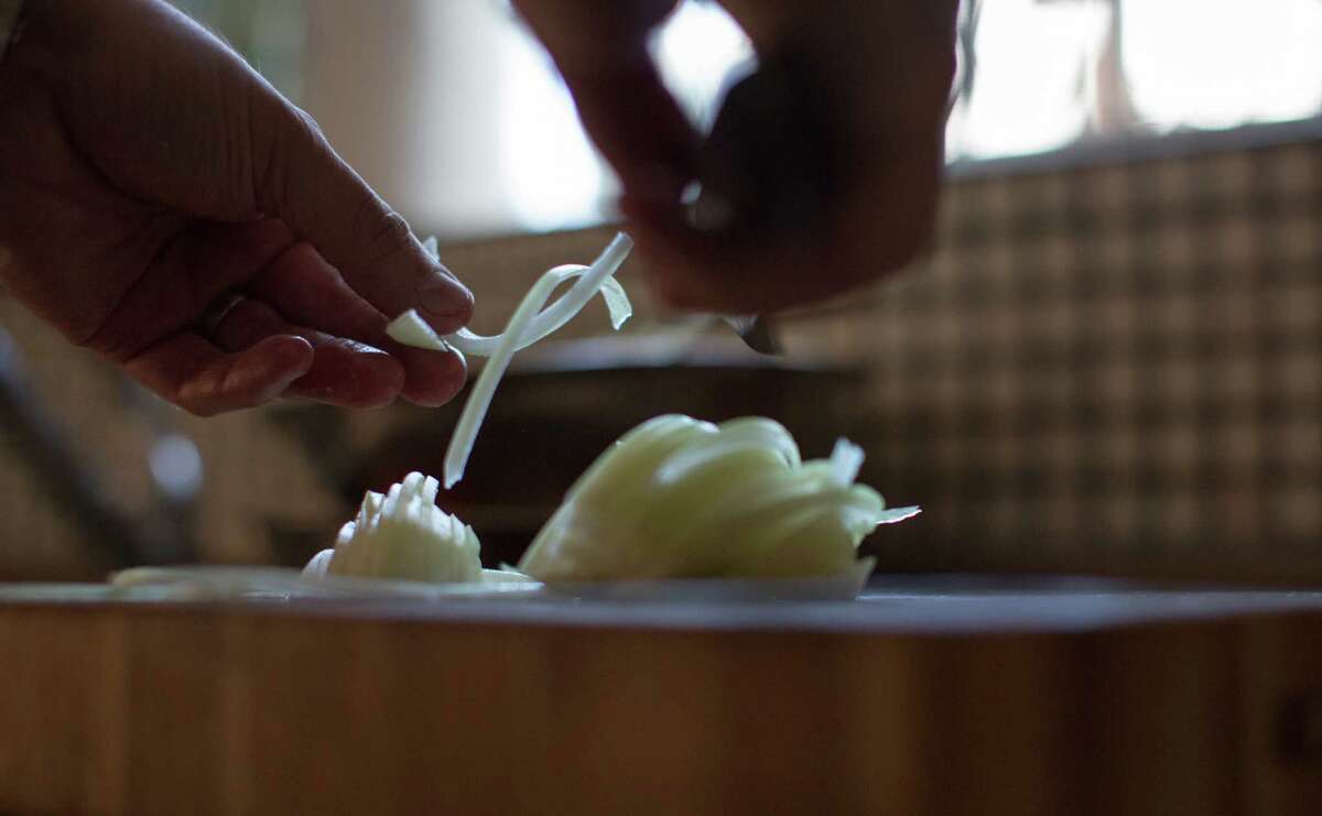 Jason Berthold carefully slices onions for his French onion soup with oxtail.