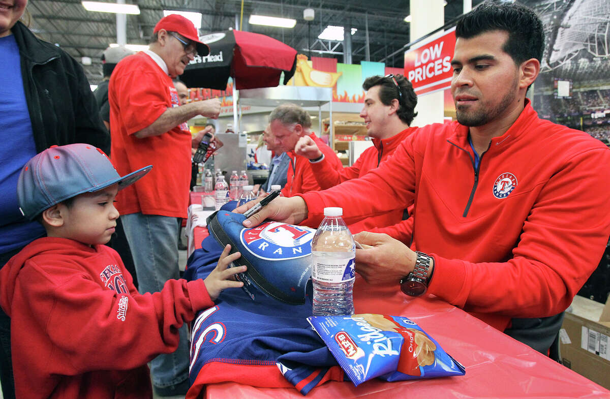 Catcher Robinson Chirinos signs a jersey for young fan Aristeo Jimenez as Ranger's baseball players sign autographs at the HEB in Universal City during a stop in their Rangers' Winter Caravan on January 16, 2015.