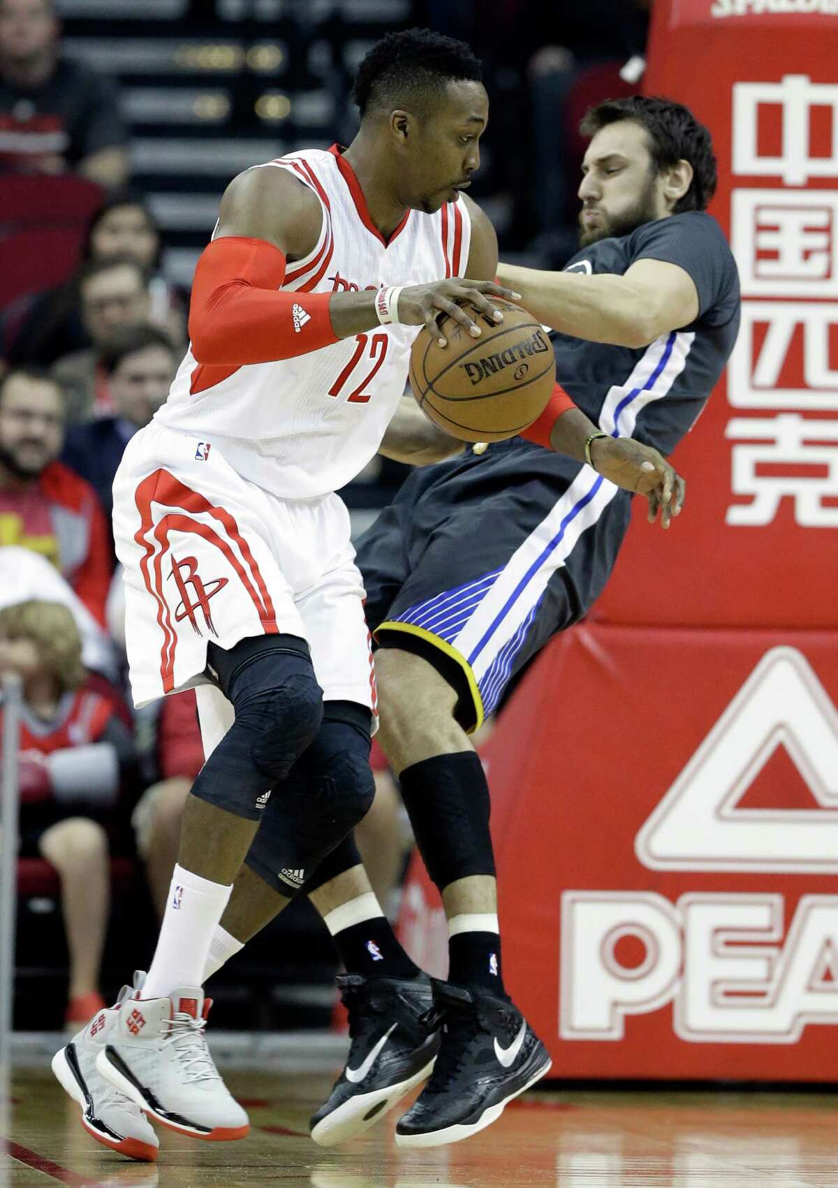 The Warriors Andrew Bogut draws a charge from the Rockets' Dwight Howard during the teams’ Jan. 17 game in Houston.