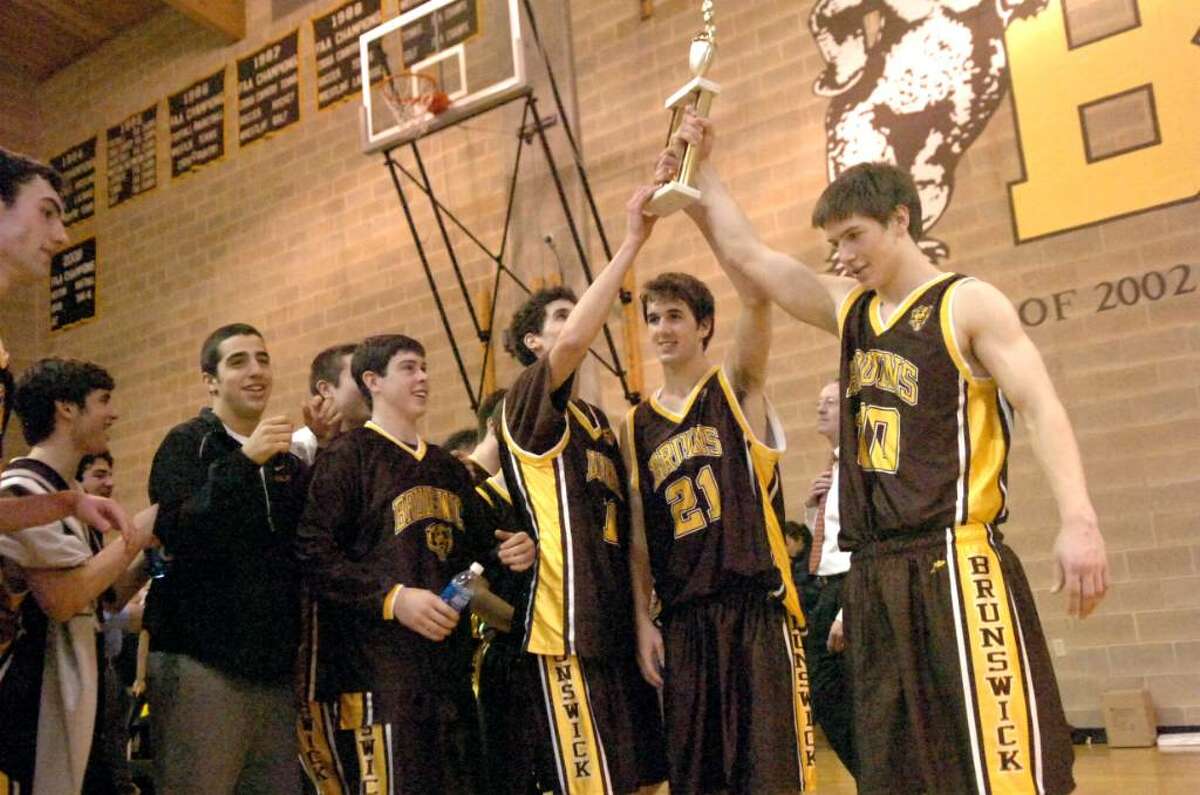 Brunswick's Zach Lynch, (#11), left, Max Barrett, (#21), and Phil Pierce, (#10) all seniors, hold up the trophy on winning the Boys Basketball FAA championship, on Sunday, February 28, 2010.