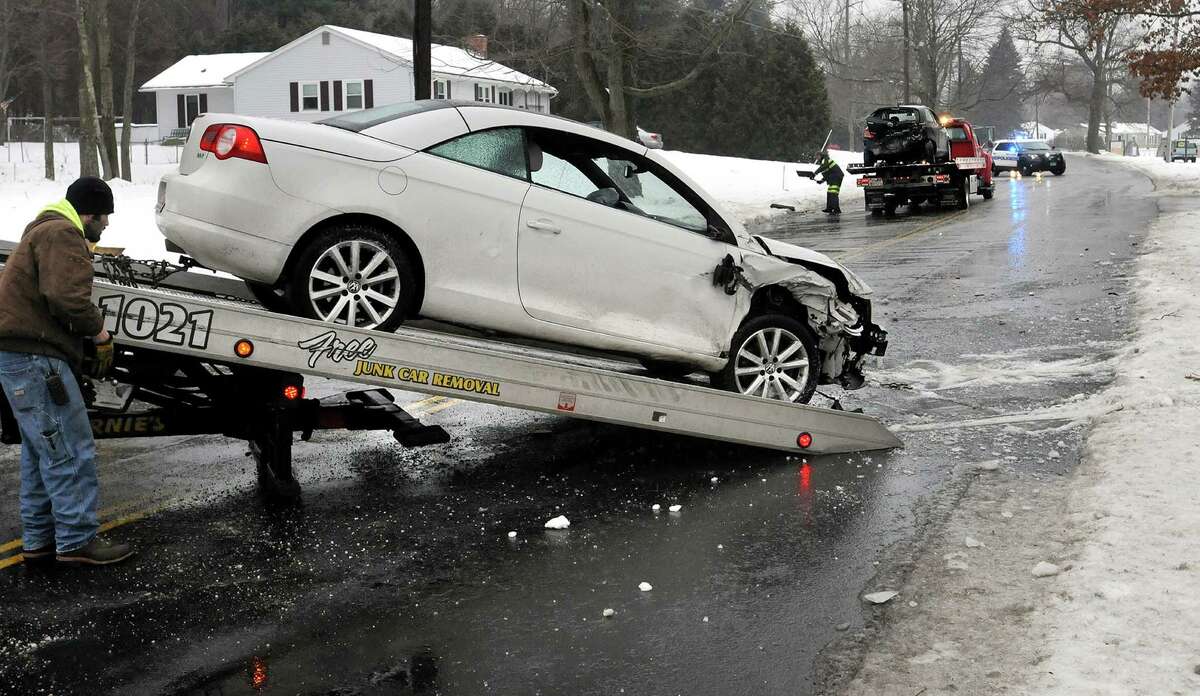 A tow truck driver, left, and first responders, behind, tend to the scene of a two-car accident Sunday, Jan. 18, 2015, in Easthampton, Mass. According to a first responder at the scene, there were no life-threatening injuries in the accident caused by icy driving conditions. (AP Photo/Daily Hampshire Gazette, Kevin Gutting)
