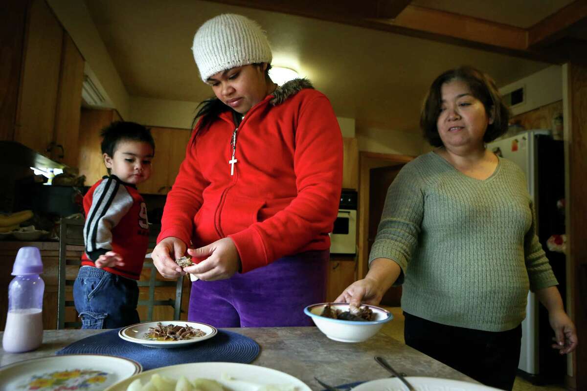 Rosalinda Maldonado, right, a member of the Interfaith Welcome Coalition, prepares a home-cooked meal for Alejandra, center, a 20 year old immigrant from Honduras, and her two year-old son Steven. The two were released from Karnes County Residential Center, a detention center, and was given shelter by Maldonado before taking them to the bus station. The young family is now on their way to be with relatives in the New England area. Wednesday, Dec. 31, 2014.