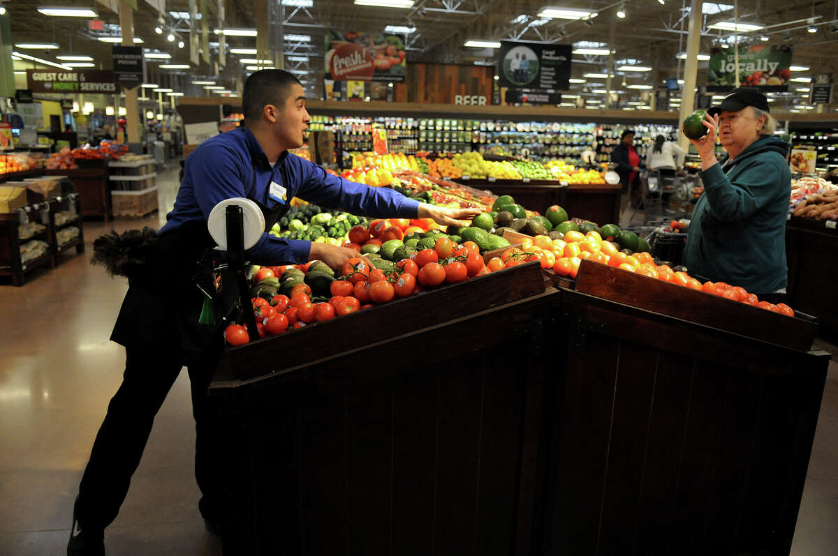 Produce Manager Gamaliel Franco, left, helps a customer with her selection of avocados at the Kroger store at 24350 Kuykendahl in Spring on Wednesday. The store opened last year.