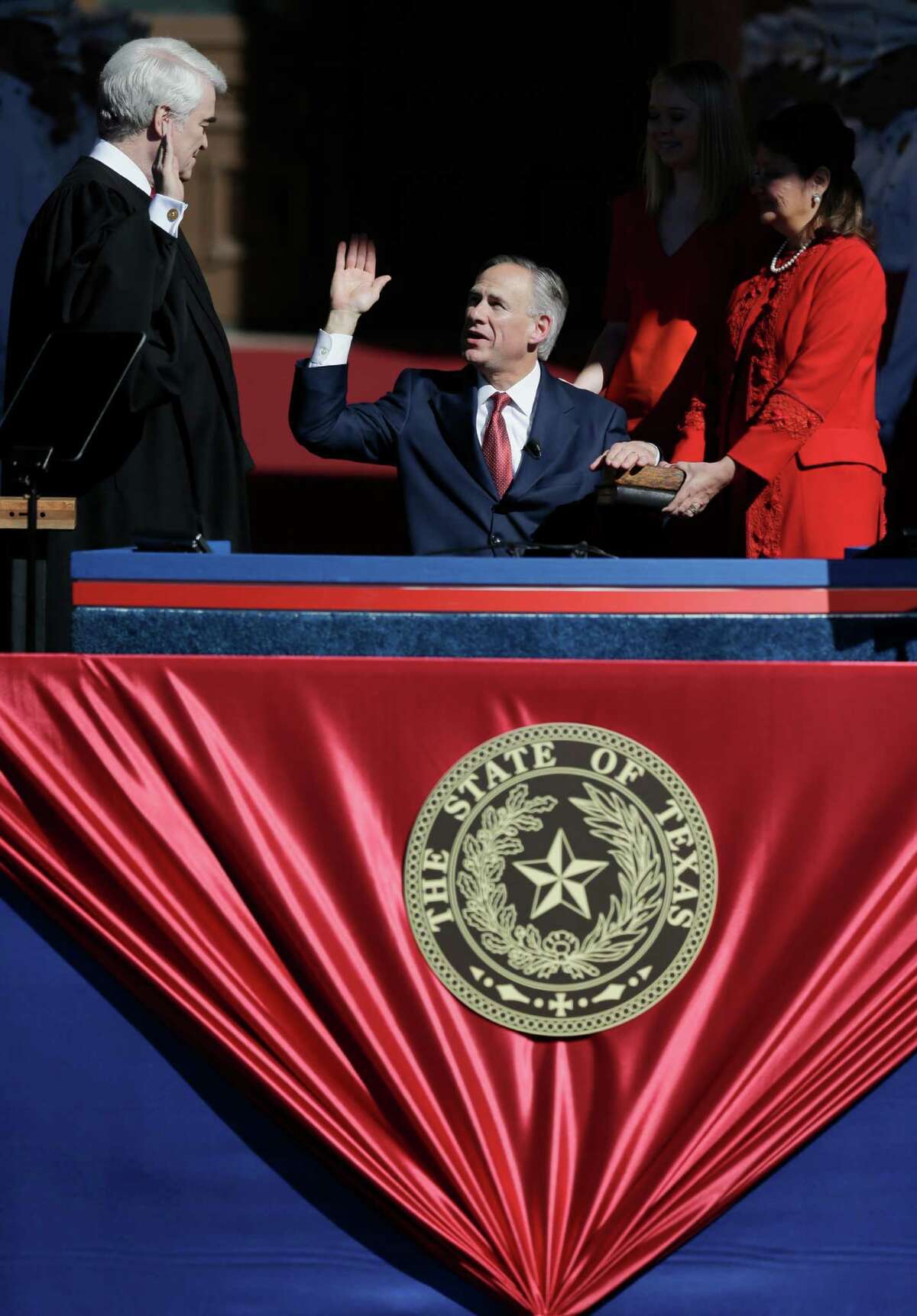 Incoming Texas Gov. Greg Abbott, center, is sworn in to office by Chief Justice Nathan Hecht, left, as Abbott's wife, Cecilia, stands at right, Tuesday, Jan. 20, 2015, in Austin, Texas. Abbott is the first Texas governor to use a wheelchair. (AP Photo/Eric Gay)