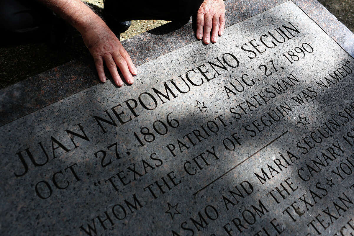 Albert Seguin Gonzales, of Texas City, touches the monument at the burial site of his fourth great grandfather, Alamo defender Juan Seguin, in 2013.