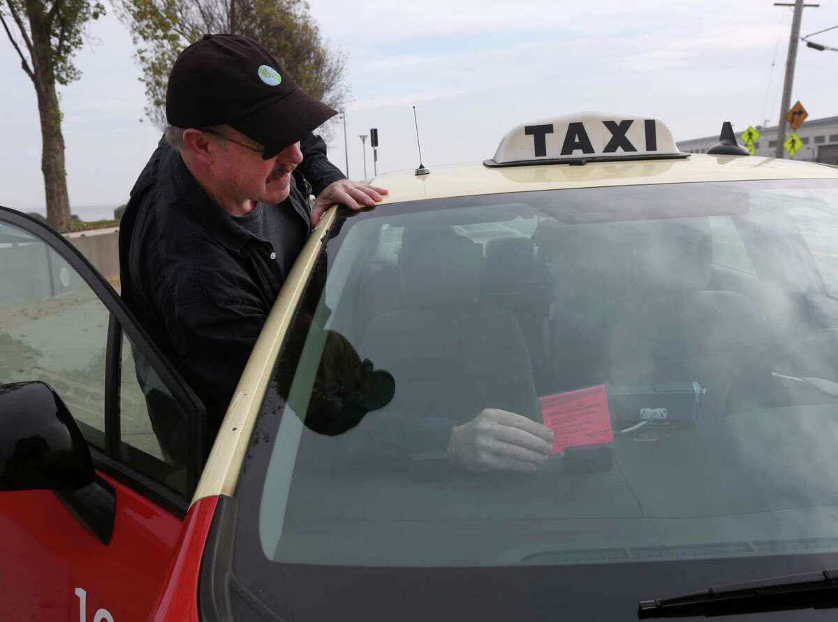 Cabdriver Gerard Rowland places his temporary medallion on the dashboard. He purchased the medallion in S.F. last year.