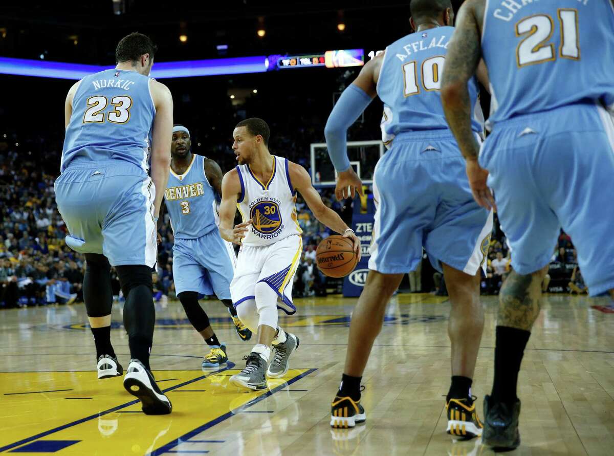 Warriors point guard Stephen Curry, who had eight assists and just one turnover in the game, sizes up a group of Nuggets defenders Monday.