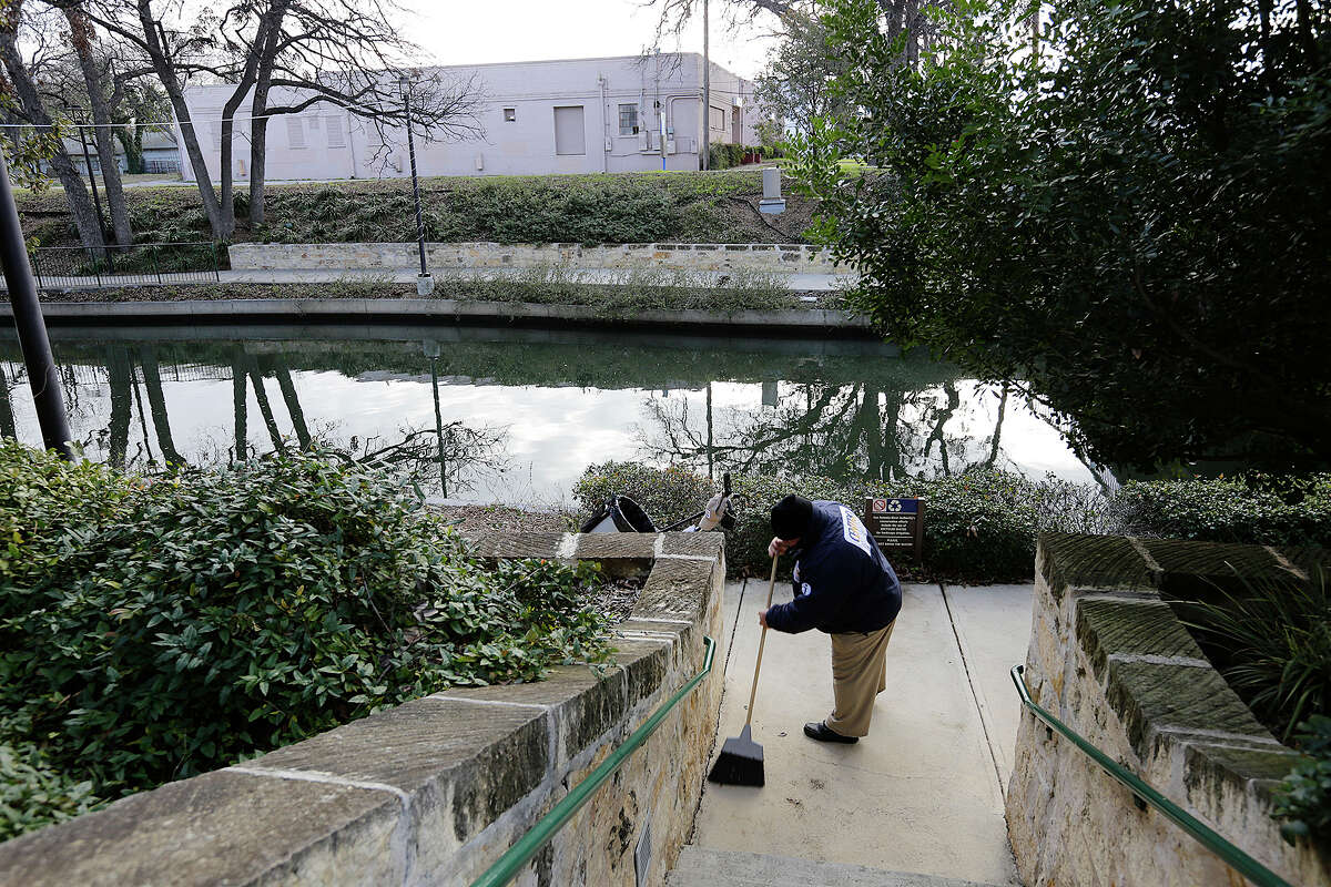 A worker cleans up the sidewalk across the San Antonio River Walk from the former Turner Club building, Jan. 15.