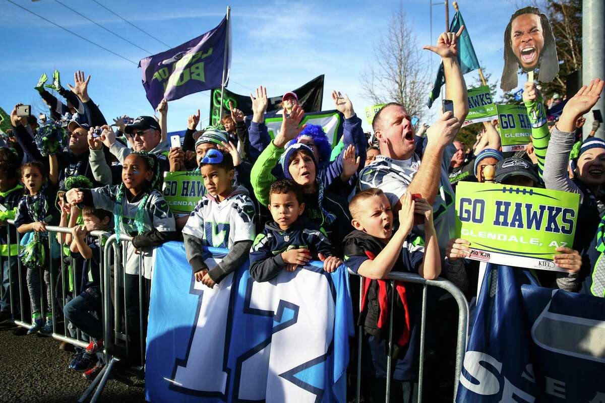Fans cheer near Seattle-Tacoma Airport as the Seattle Seahawks buses drive past.