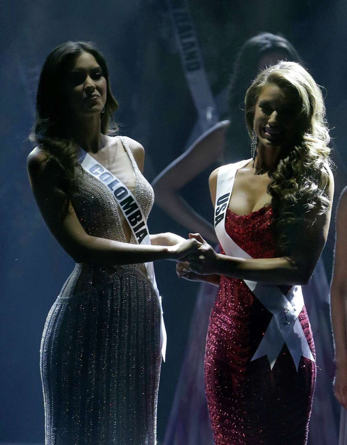 Paulina Vega of Colombia, left, and Nia Sanchez of the U.S., hold hands as the wait for the announcement of who will be selected as Miss Universe, Sunday, Jan. 25, 2015, during the Miss Universe pageant in Miami.