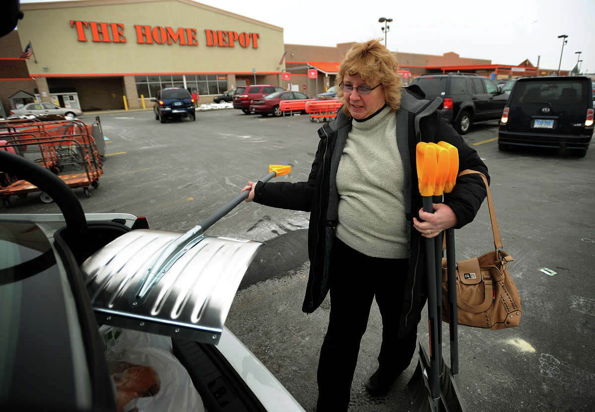 In preparation for the snow, Debbie Mica, of Shelton, loads four new snow shovels into her car outside the Home Depot in Stratford, Conn. on Monday, January 26, 2015.
