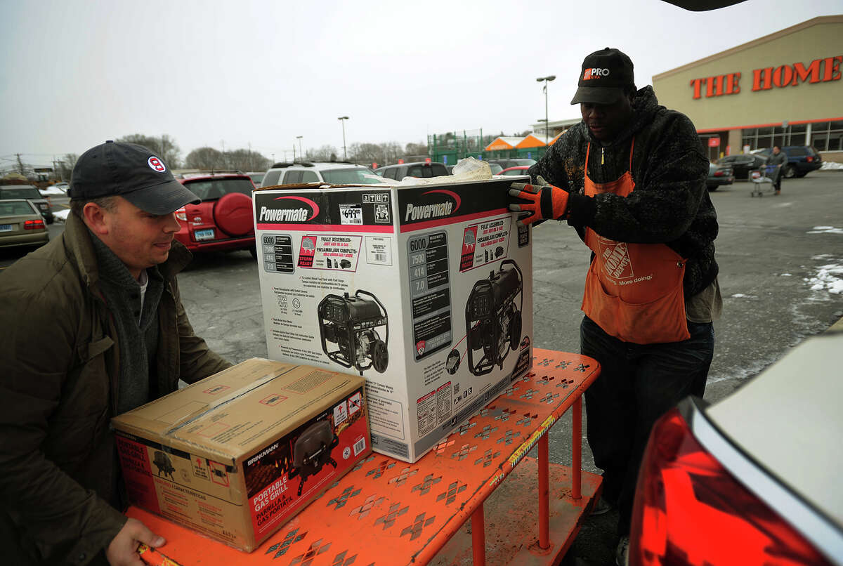With a one week old baby at home, Chris Howe, right, of Stratford, loads a generator into his car with the help of Home Depot employee David Perry, of Stratford, in preparation for the coming blizzard in Stratford, Conn. on Monday, January 26, 2015.