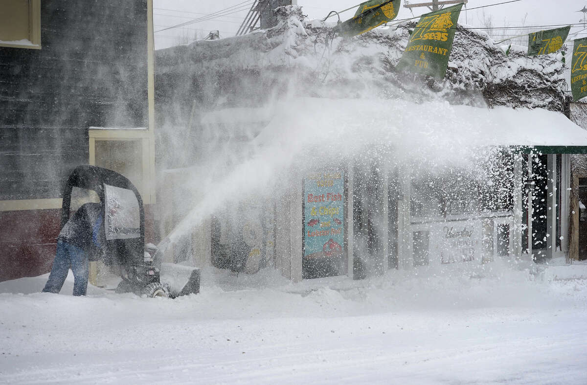 Rick Smith, owner of the Seven Seas restaurant, clears snow from the sidewalks in front of his and neighboring businesses in downtown Milford, Conn. on Tuesday, January 27, 2015.