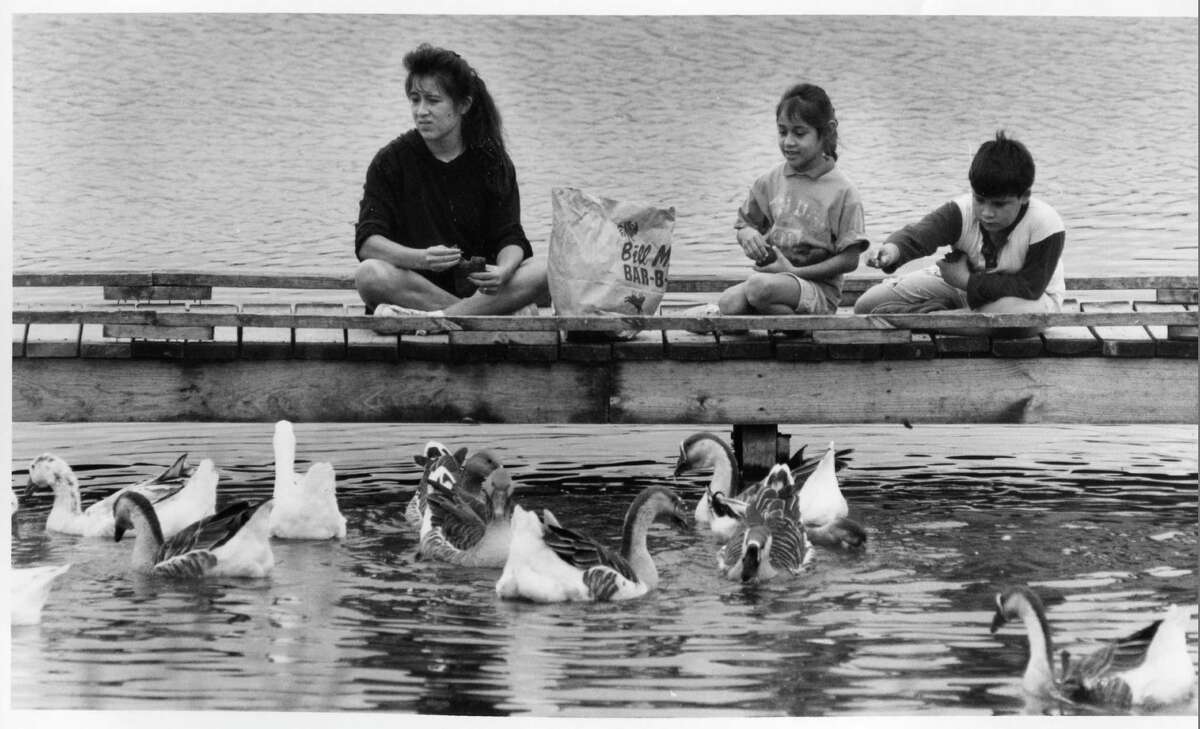 Monica Cardenas, along with her daughter Tiffany Cardenas and son Steven Ramos, feed bread to the ducks and geese after she finishes running around the lake, October 11, 1993.