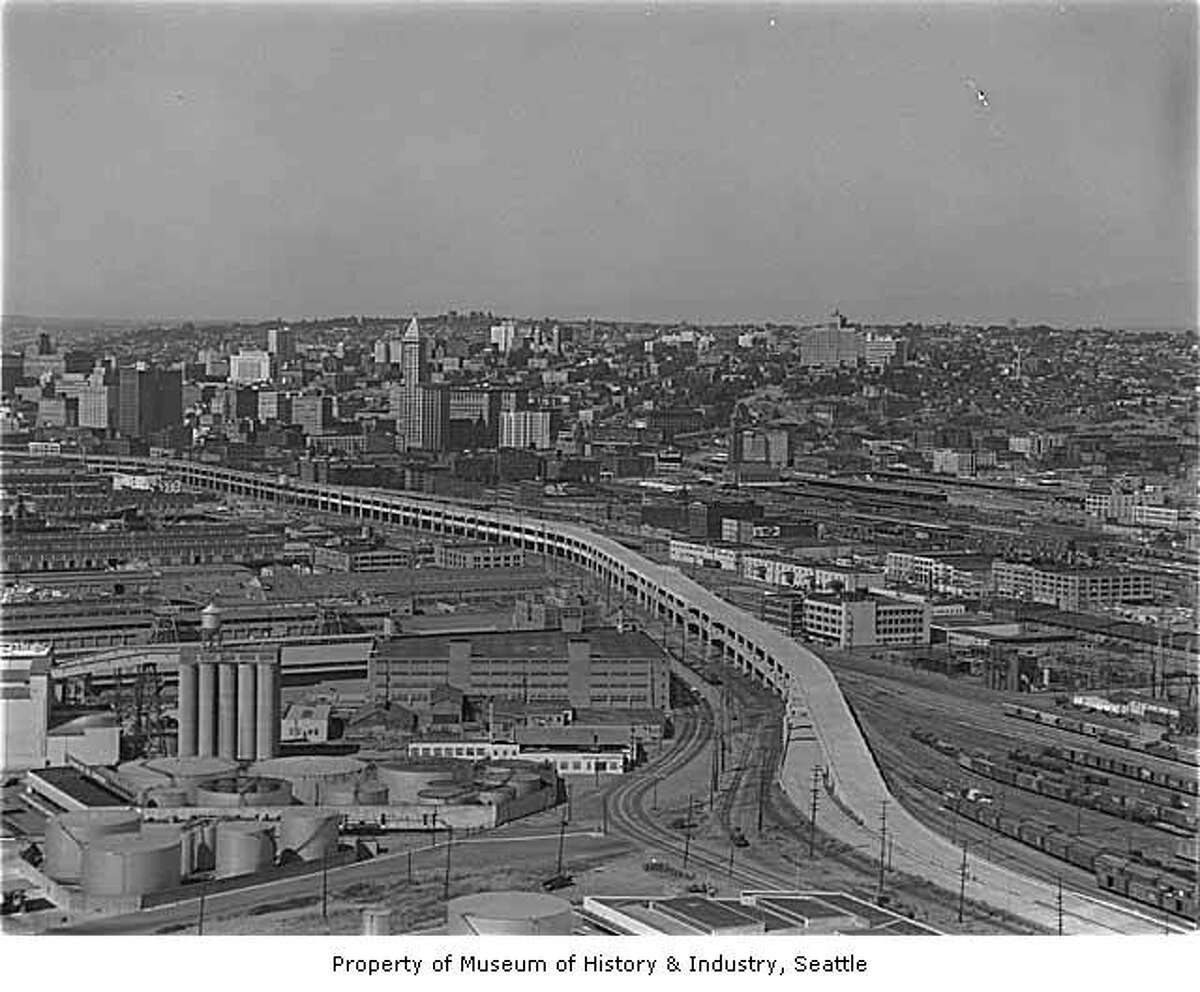 Aerial of Alaskan Way Viaduct extension south to Spokane Street with a view northeast toward Seattle, 1959 - MOHAI caption: Seattle's Alaskan Way Viaduct carries traffic over the waterfront area, linking the northern part of the city to the industrial area south of the central business district. The first unit of the elevated roadway, from Battery Street to Dearborn Street, was completed in 1953 and a southern extension in 1959 .
