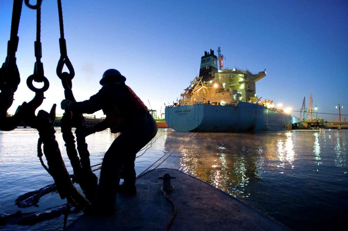 A lineman lets go of the mooring lines of a ship early in the morning.. Photo by Lou Vest, a Houston Ship Channel pilot.