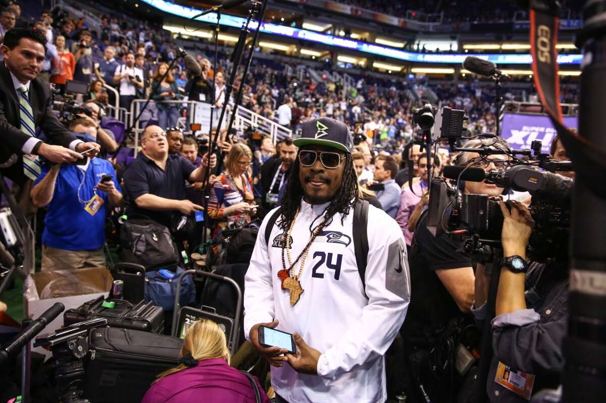 Marshawn Lynch wades through members of the media to his podium during Super Bowl XLIX Media Day on Tuesday, January 27, 2015, at the US Airways Center in Phoenix, Arizona.