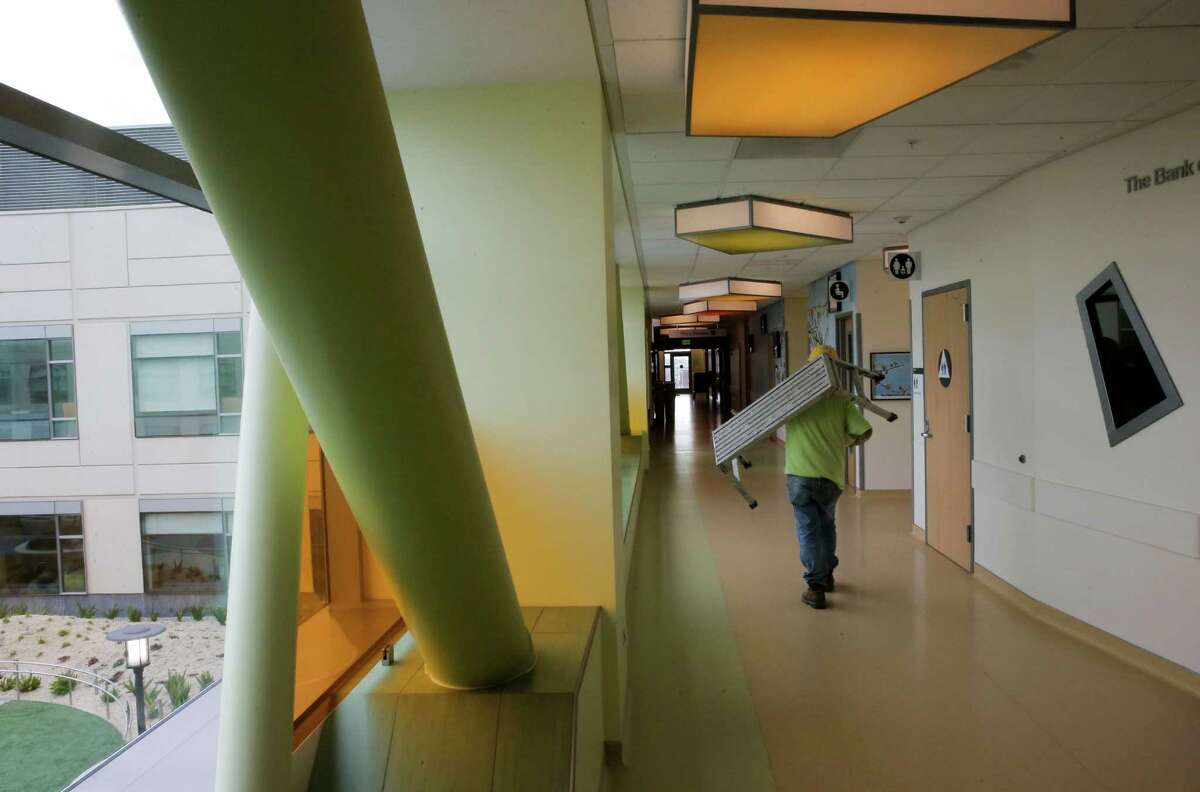 A man carries a piece of furniture down a hallway inside the UCSF Medical Center at Mission Bay.