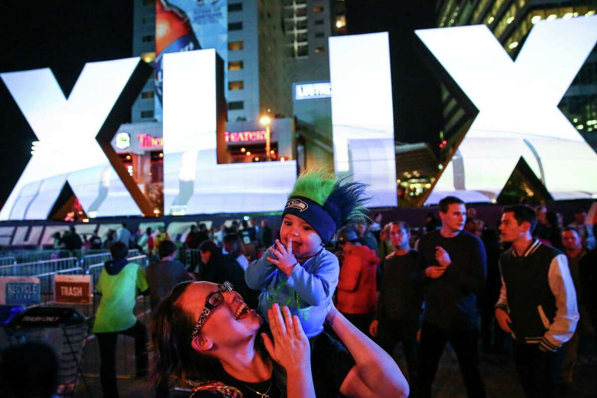 Arielle Fox, originally from Seattle, and her son, Taj Khader, 7 months, have fun at the kickoff of Verizon Super Bowl Central on Wednesday, Jan. 28, 2015 in downtown Phoenix. Super Bowl Central is a free, football-themed outdoor event for fans. One million visitors are expected to attend Super Bowl Central.