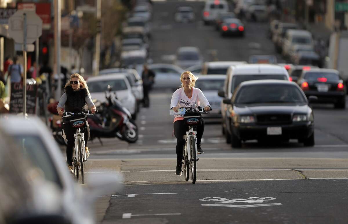 Sarah Ritchie, right, and Candice Taylor, left, visitors from South Africa, ride their bikes on Polk Street near Broadway in San Francisco, Calif., on Wednesday, January 28, 2015. Polk Street improvements might make the narrow street tougher to negotiate as the improvements are designed to make this well traveled bike corridor safer.