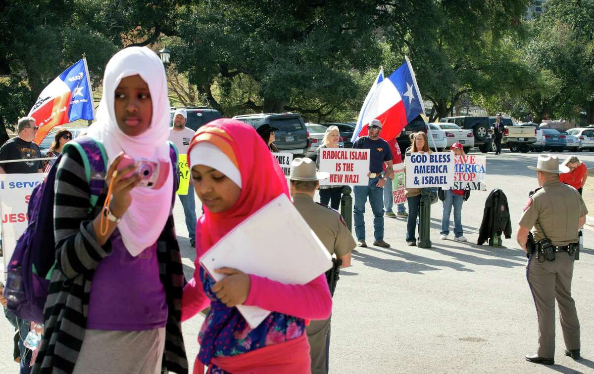 Amina Hassan, left, 11, of Grand Prairie, and Ayefa Klair, 10 of Irving, are faced with anti-Muslim protesters at the Texas Muslim Capitol Day in Austin, Texas, on Thursday, Jan. 29, 2015. Hundreds of Muslims from around Texas gathered for the Council on American-Islamic Relations rally and to talk to their representatives about legislation that's important to them. (AP Photo/Austin American-Statesman, Jay Janner) AUSTIN CHRONICLE OUT, COMMUNITY IMPACT OUT, INTERNET AND TV MUST CREDIT PHOTOGRAPHER AND STATESMAN.COM, MAGS OUT