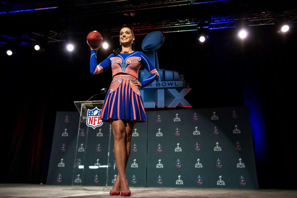 Pop singer starlet Katy Perry prepares to toss a football into a crowd of media at Super Bowl XLIX's Halftime Show Press Conference Thursday, January 29, 2015, at the Phoenix Convention Center in Arizona. American actress and singer-songwriter Idina Menzel will perform for the pregame show and Katy Perry will take on the halftime show.