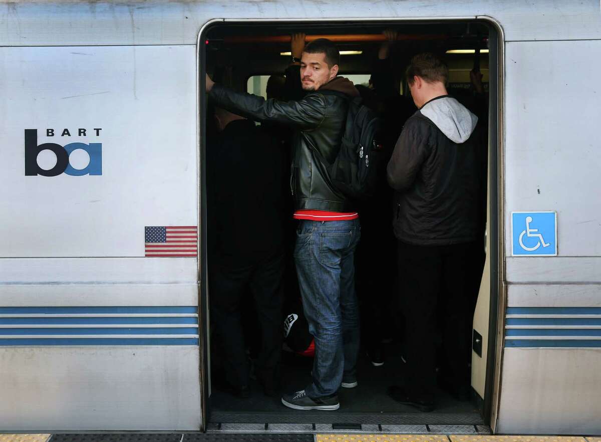 Passengers squeeze into a crowded westbound train at the West Oakland BART Station.
