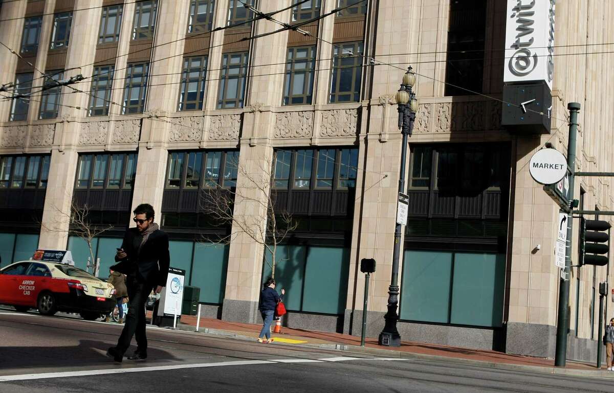 A pedestrian crosses the street in front of the Twitter building that was the old Western Furniture Exchange and Merchandise Mart on Market Street on April 25, 2014 in San Francisco, Calif. Tech companies are buying historic buildings within the city thus helping to protect these landmarks.