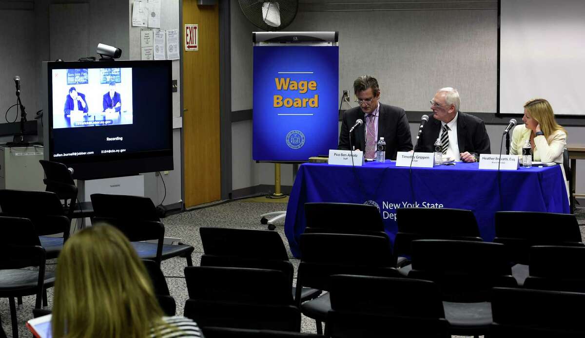 Department of labor staff member Pico Ben-Amotz, left, works with Wage Board members Timothy Grippern, center, and Heather Briccetti as they speak to board member Peter Ward via video conference Friday, Jan. 30, 2015, at the Labor Department in Albany, N.Y., to develop recommendations any modifications that should be made to the required cash wage rates and the allowable credits for tips, meals and lodging for food service workers and service employees in the hospitality industry. (Skip Dickstein/Times Union)