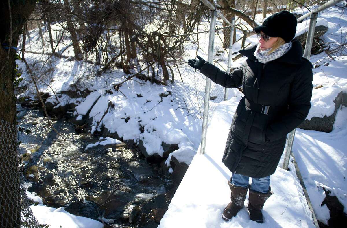 Dawn Fortunato walks near a stream that passes the transfer station and is part of concerns she and her neighbors have about air, soil and water contamination in the area in Greenwich, Conn., on Saturday, January 31, 2015.
