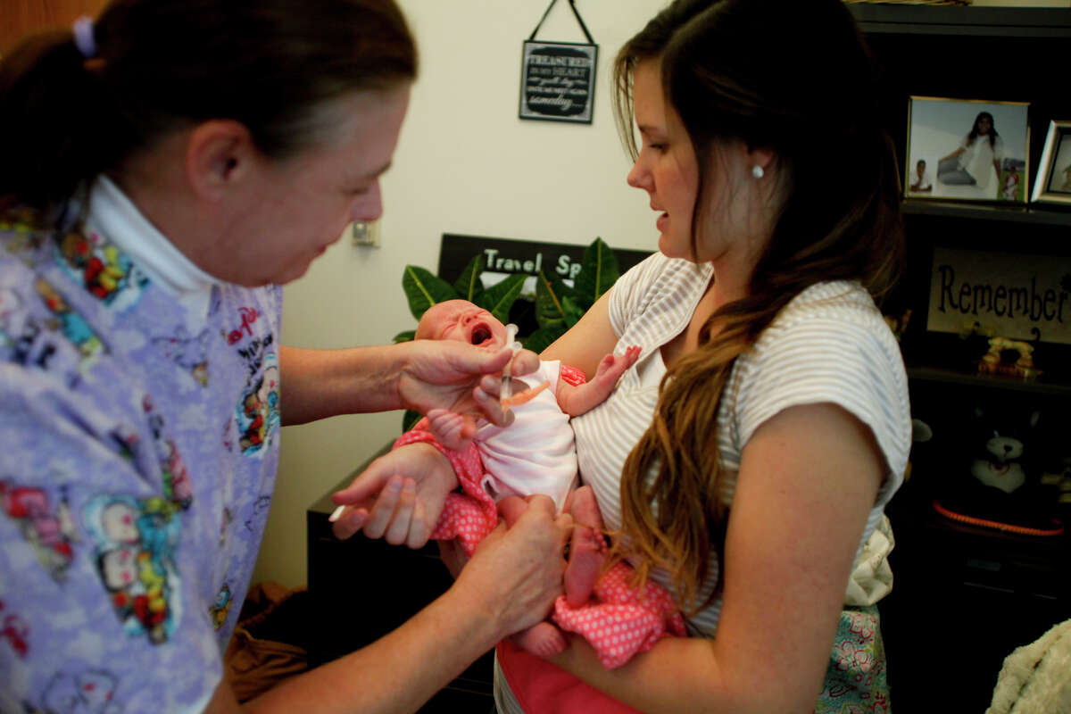 Nurse Bonnie Hardy gives McCall Messick a measles vaccination while Messick's mother, Amy, holds her at the Utah County Health Department in Provo on Wednesday, Jan. 7, 2015. (AP Photo/The Daily Herald, Ian Maule)