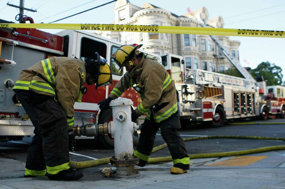 Firefighters unscrew fire hoses from hydrants after battling a four-alarm fire which damaged 17 units in four residential buildings on the 1500 block of McAllister Street between Divisadaro and Scott streets in San Francisco, Calif. Saturday, January 31, 2015.