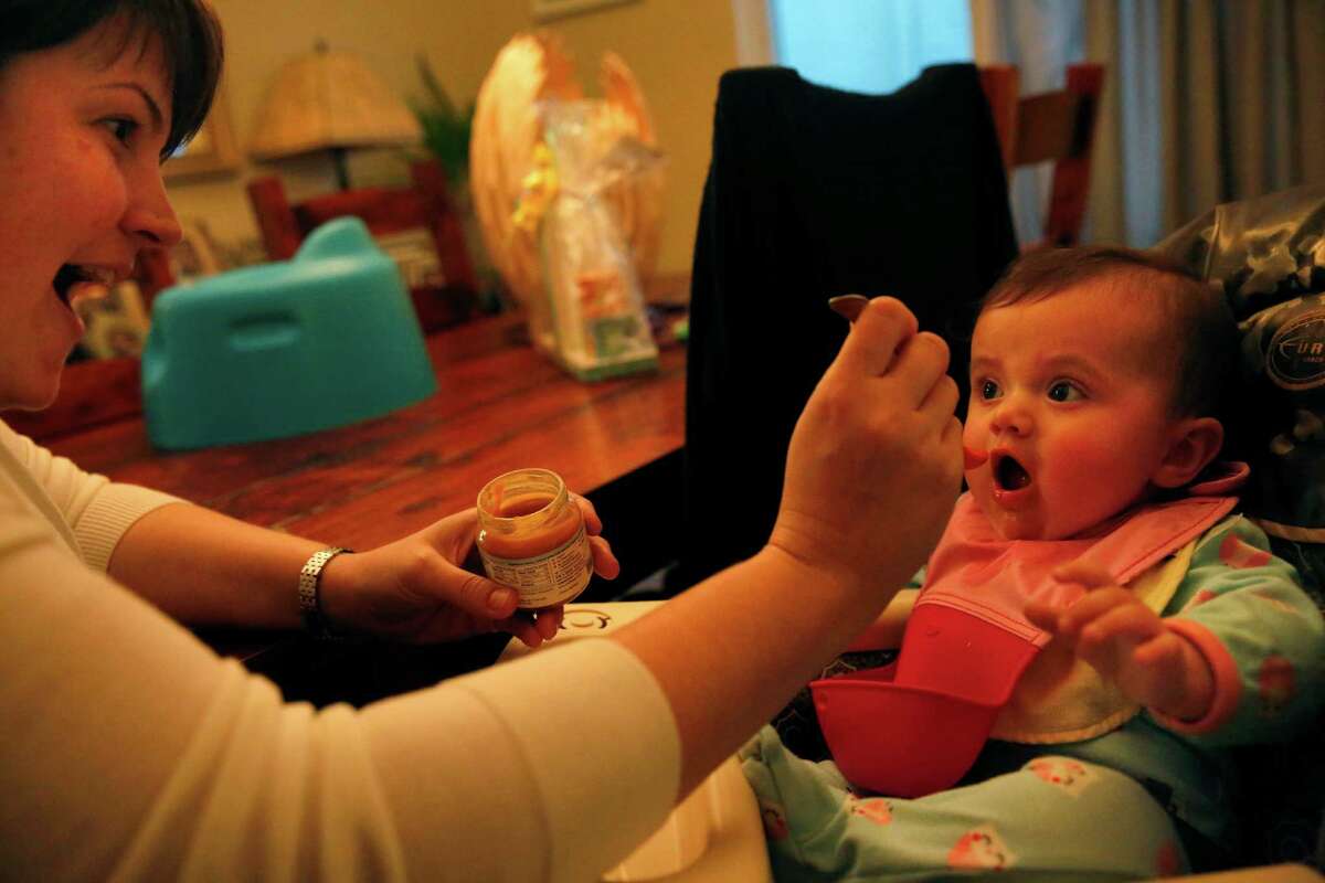 Livia Simon, 6 mo., gets fed dinner from her mom Jennifer at the Simon home Jan. 30, 2015 in Oakland, Calif. Livia, who is almost seven months and not old enough for a vaccine, was put in a 21 day quarantine after getting exposed to a child who had the measles at their pediatrician's office.
