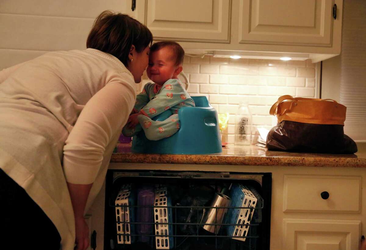 Jennifer Simon shares a moment with her daughter Livia 6 mo., as she does the dishes at the Simon home Jan. 30, 2015 in Oakland, Calif. Livia, who is almost seven months and not old enough for a vaccine, was put in a 21 day quarantine after getting exposed to a child who had the measles at their pediatrician's office.