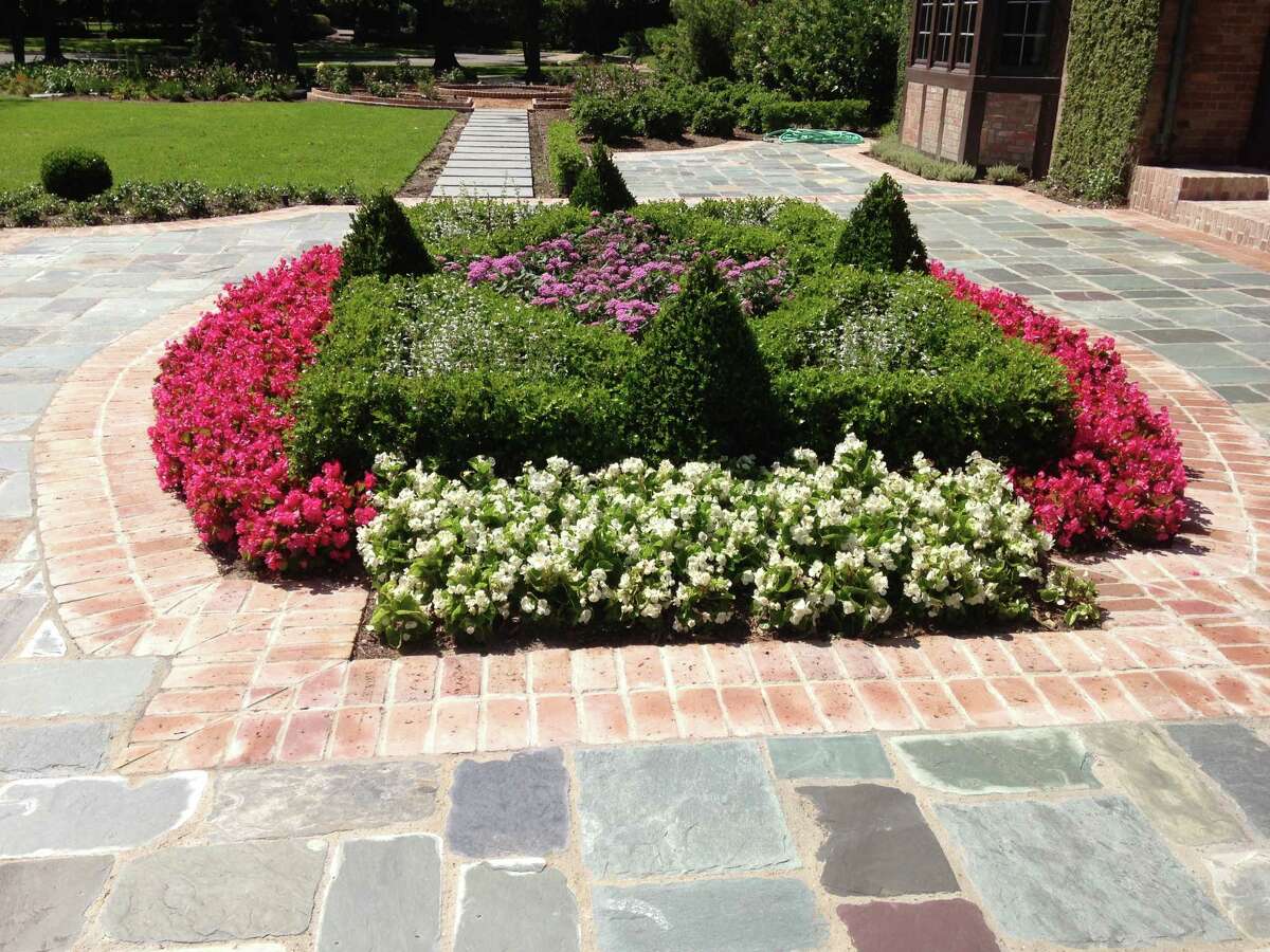 The brick-and-slate "greeting" area is accented with a geometric bed with clipped boxwood and seasonal color. 