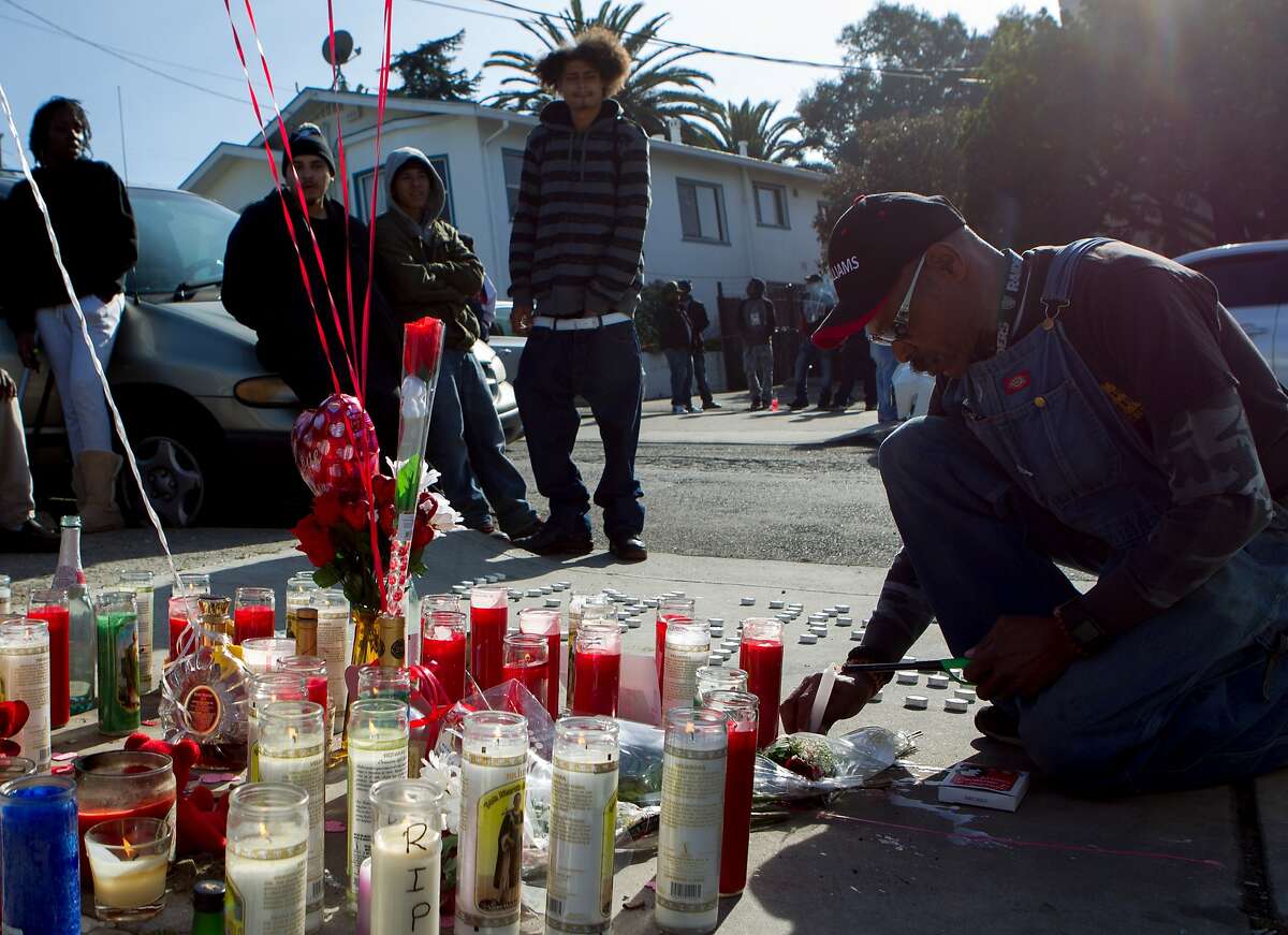 Steve Wilson (right) lights a candle in memorial for Dominic Newton, 37, at the site of the incident near 94th Avenue and MacArthur Boulevard, Tuesday, Feb. 3, 2015, in Oakland, Calif. Newton was a Bay Area rapper known by his stage name "The Jacka" who was shot and killed Wednesday night.
