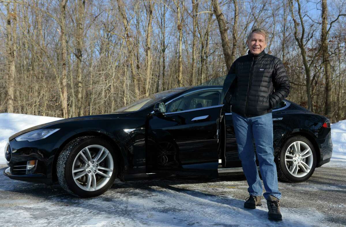 Roger Van Brussel, a Milford resident and business owner, stands in front of his new Tesla Model S 85 Thursday, Feb. 5, 2015, in Milford, Conn. Van Brussel had to leave the state to purchase the electric car but Connecticut is contemplating changing its laws so that Tesla can sell its cars here. Currently, only franchised car dealerships can sell cars in this state, not manufacturers.