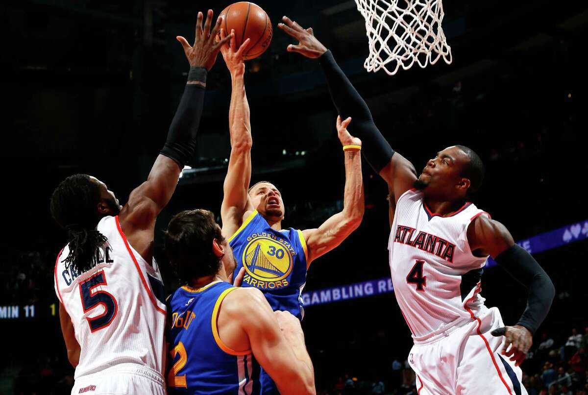 Stephen Curry (30) of the Warriors attacks the basket against DeMarre Carroll (5) and Paul Millsap (4) of the Hawks at Philips Arena in Atlanta on Friday night.