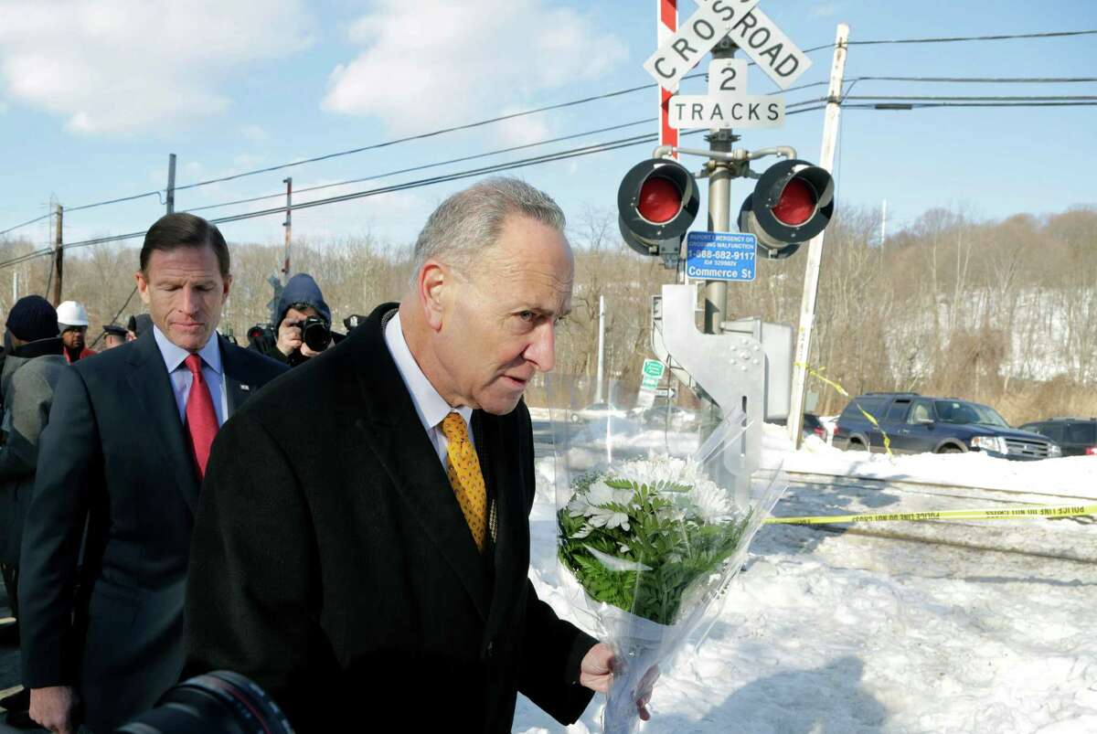 Sen. Richard Blumenthal, D-Conn., left, and Sen. Charles Schumer, D-NY, bring a bouquet of flowers to place at a railroad crossing, Friday, Feb. 6, 2015, in Valhalla, N.Y. On Tuesday a car collided with a Metro-North Railroad train at the same location, killing the car's driver and five train passengers. (AP Photo/Mark Lennihan) ORG XMIT: NYML205
