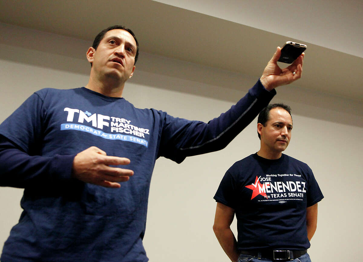 State Senate District 26 candidate Trey Martinez Fischer (left) plays a message from Henry Cisneros after a question was brought up to him about a claim that Cisneros was endorsing him as Jose Menendez listens Saturday Feb. 7, 2015 during the Northeast Bexar County Democrats meeting at Tri Point. Early voting for the special election runoff begins on Monday, Feb. 9.