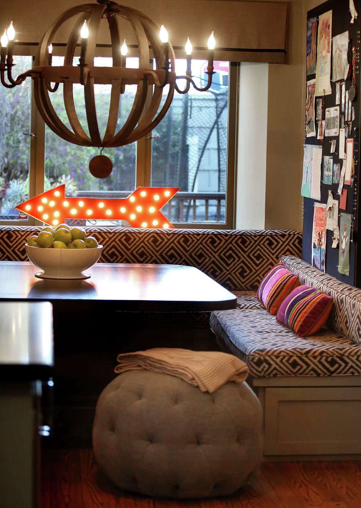 The banquette in the kitchen of Chad Olcott and Laura Pochop, who own the shop Mulberry’s Market in Piedmont, features a black-and-white ikat print with striped pillows. The chandelier, made from a wine barrel, is from Noir, and another whimsical touch is the marquee arrow from Urban Outfitters. Oatmeal linen pouf from Cisco Brothers.