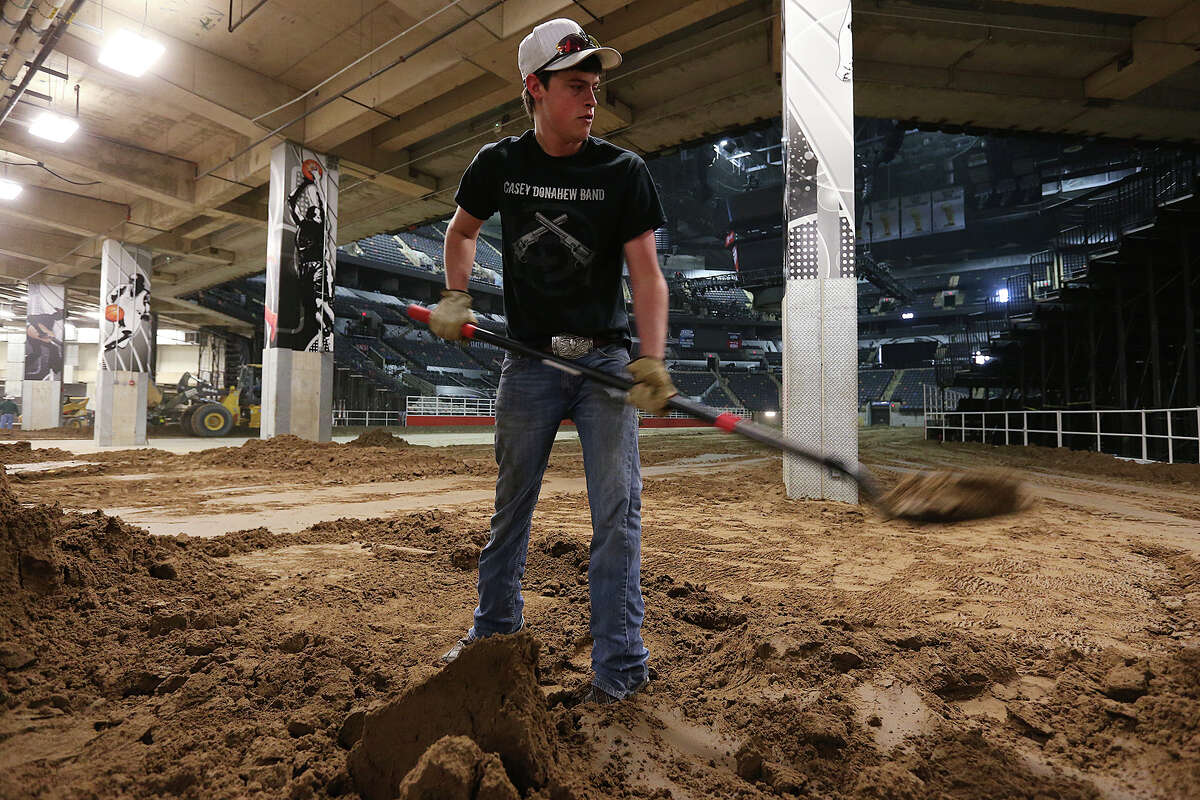 Charles Brumley, 17, of Lytle, packs dirt toward the edges Monday as workers turn the AT&T Center into the home of the San Antonio Stock Show & Rodeo.