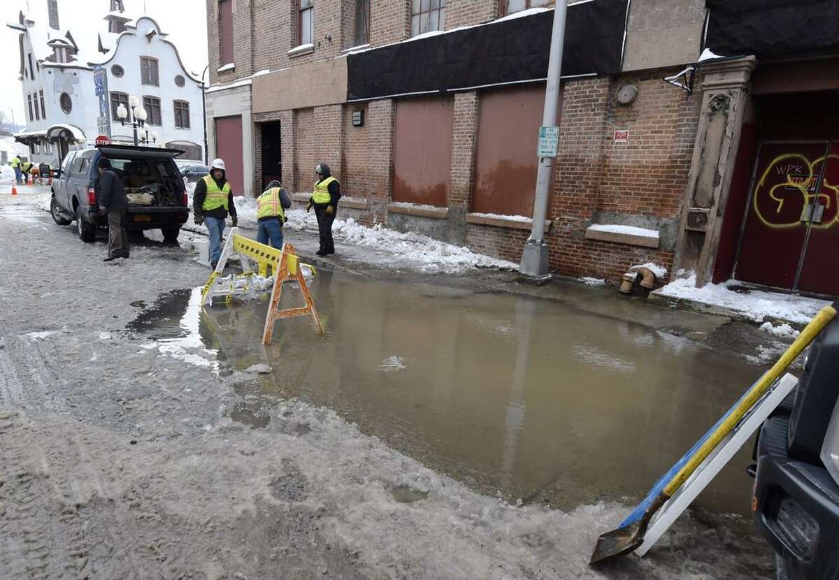 As water pours from the sidewalk, Albany water department workers begin work on a possible water-main break on Division Street Monday morning. (Skip Dickstein / Times Union)