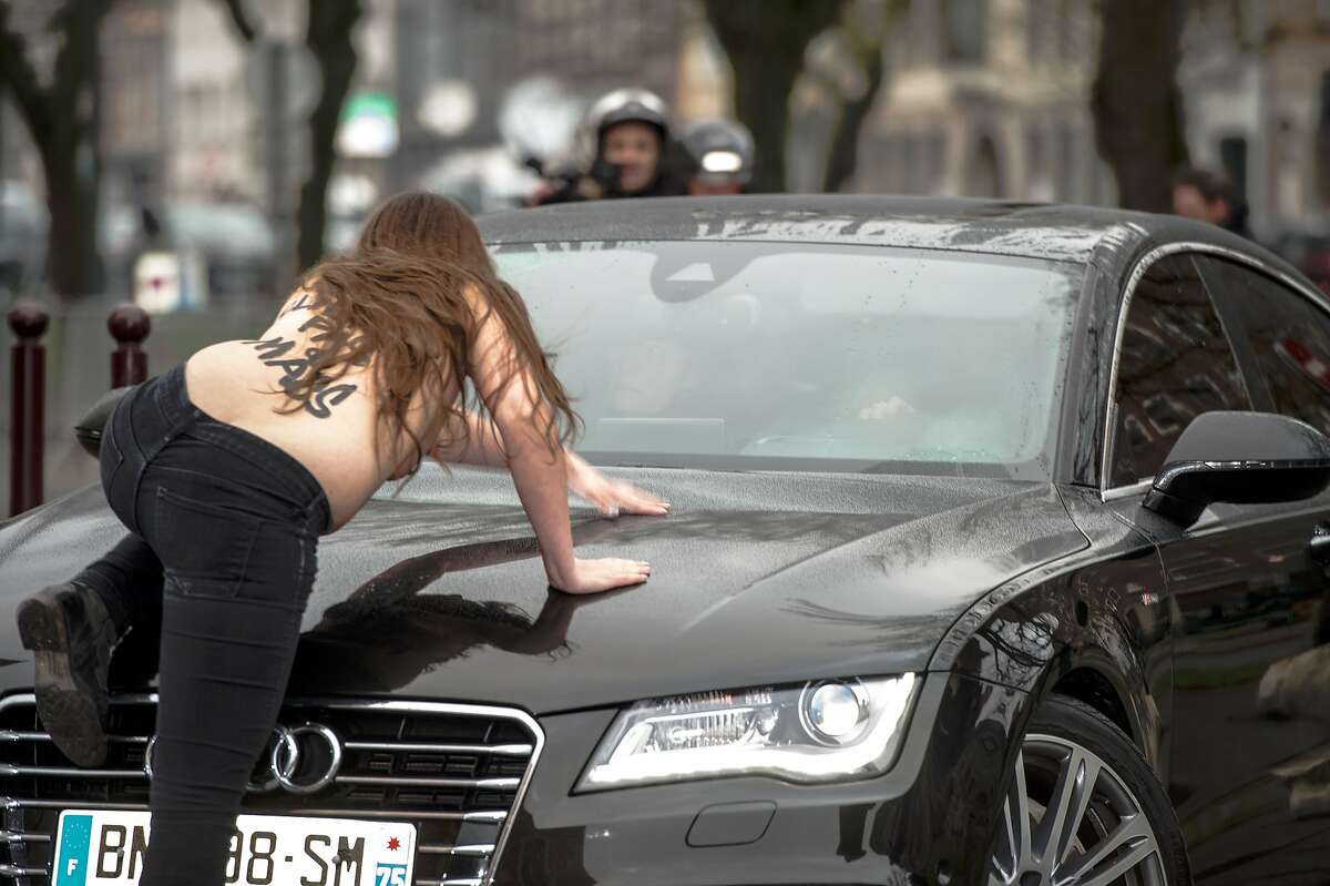 PIMP MY RIDE: A Femen activist jumps on a car carrying former IMF chief Dominique Strauss-Kahn as he arrives for his trial in Lille, France. She was joined by two other topless women hurling insults at Strauss-Kahn, who has been charged with "aggravated pimping." All three were hauled away by police.