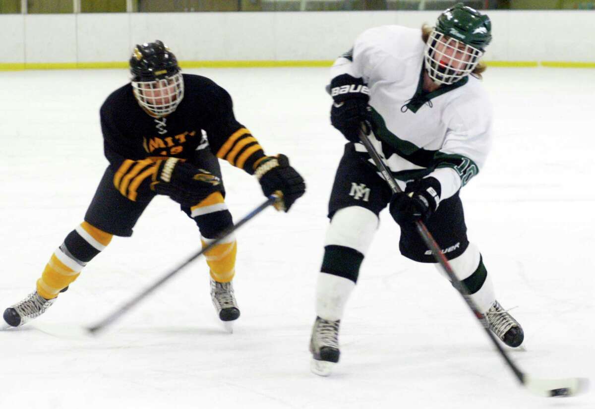 Nate Capriglione of the Green Wave shrugs off the efforts of a rival defender to send a shot on net during New Milford High School ice hockey's 4-2 victory over Amity Regional , Feb. 7, 2015 at Canterbury School.