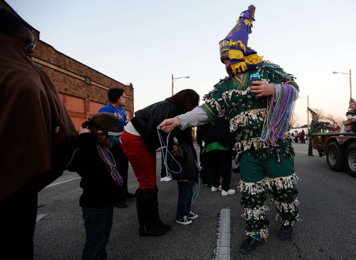 Costumed marchers hand out strands of beads as they move into downtown Port Arthur on Thursday evening. Port Arthur held the Courir du Mardi Gras Parade along Lakeshore Drive on Thursday night. The small parade acts as one of the opening ceremonies of Mardi Gras in the city. Photo taken Thursday, 2/27/14 Jake Daniels/@JakeD_in_SETX